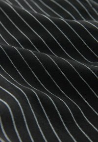 Čierna tkanina s úzkymi bielymi a svetlomodrými pruhmi, s textúrovaným povrchom a jemným leskom. Vzor vytvára diagonálny tok.