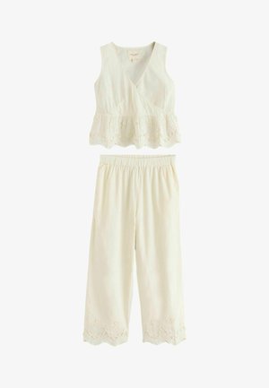 Sleeveless white crop top with V-neck and scalloped lace hem, paired with wide-leg pants featuring matching lace trim at cuffs.