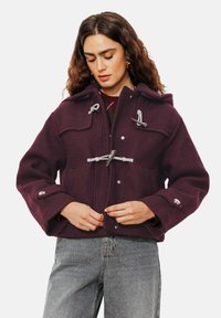 Veste en laine bourgogne avec capuche, fermetures à toggles, deux poches avant et accents en métal argenté. Fini texturé et coupe décontractée.
