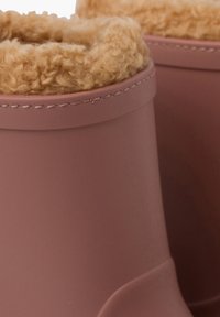 Roze rubber laarzen met een zachte, beige fleece voering aan de bovenkant. Glad exterieur met een afgerond ontwerp en gestikte accenten.