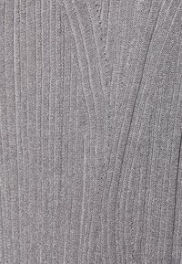 Tissu texturé gris clair avec un motif côtelé vertical, présentant des lignes variées qui créent une apparence naturelle semblable au bois.