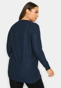 Mörkblå, långärmad tröja i strukturerad stickad tyg, med rundad halsringning och något längre bakre fåll med sidslitsar.