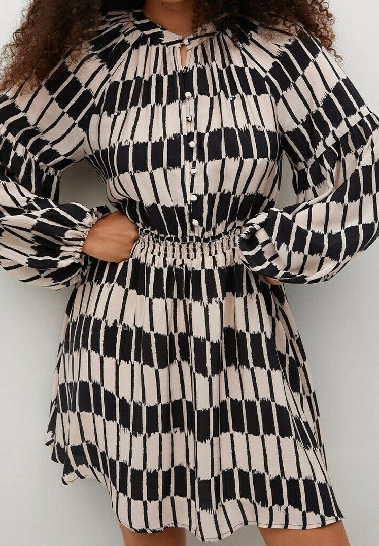 Vestido de patrón negro y beige con mangas abullonadas, cinturilla elástica, botones en la parte delantera y detalle de cuello con ojal. Textura de tela suave.