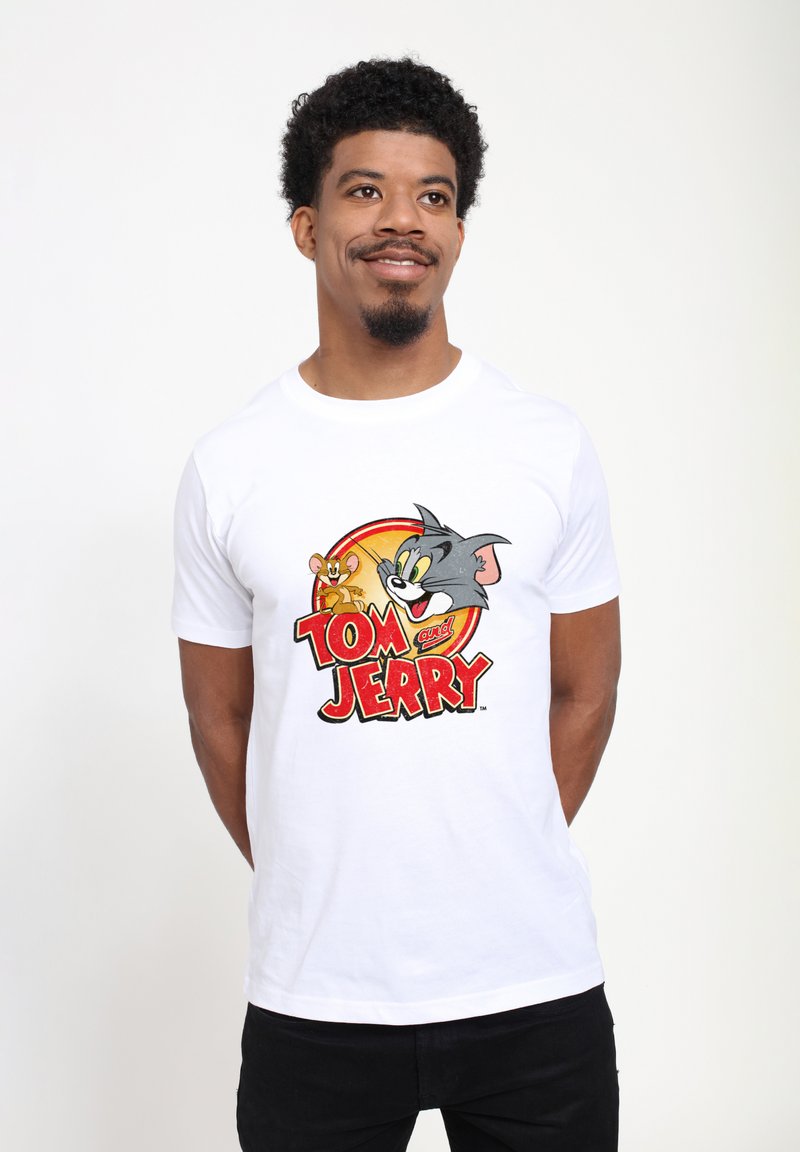 Hvid bomulds T-shirt med en farverig grafik af Tom og Jerry og fed tekst nedenfor, der viser en glat tekstur og klassisk tegnestil.