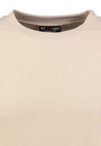 T-shirt in cotone a coste beige con colletto rotondo e un'etichetta con "KEY LARGO" all'interno. Texture liscia con una forma aderente.