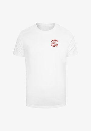 Valge puuvillane T-särk, millel on punane graafiline trükk pitsaviilu ja tekst "TAISETÜKK PARADIISIST" selle kohal. Lühikesed varrukad, ümar kaelus.