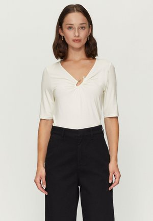 Witte short-sleeve top met een V-hals en een decoratieve twist in het midden, gecombineerd met zwarte high-waisted broek. Eerlijke textuur, schoon ontwerp.