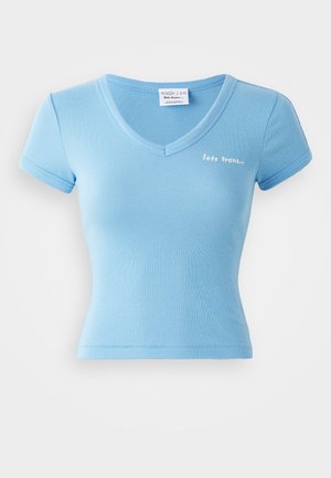 Camiseta ajustada de color azul claro, hecha de algodón elástico. Presenta un escote en forma de V profundo y mangas cortas. Incluye texto blanco en el pecho.
