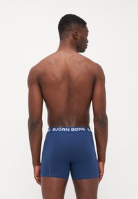 Navy blue boxer briefs made from soft fabric, featuring a white elastic waistband with "BJÖRN BORG" branding. No visible patterns or accents.