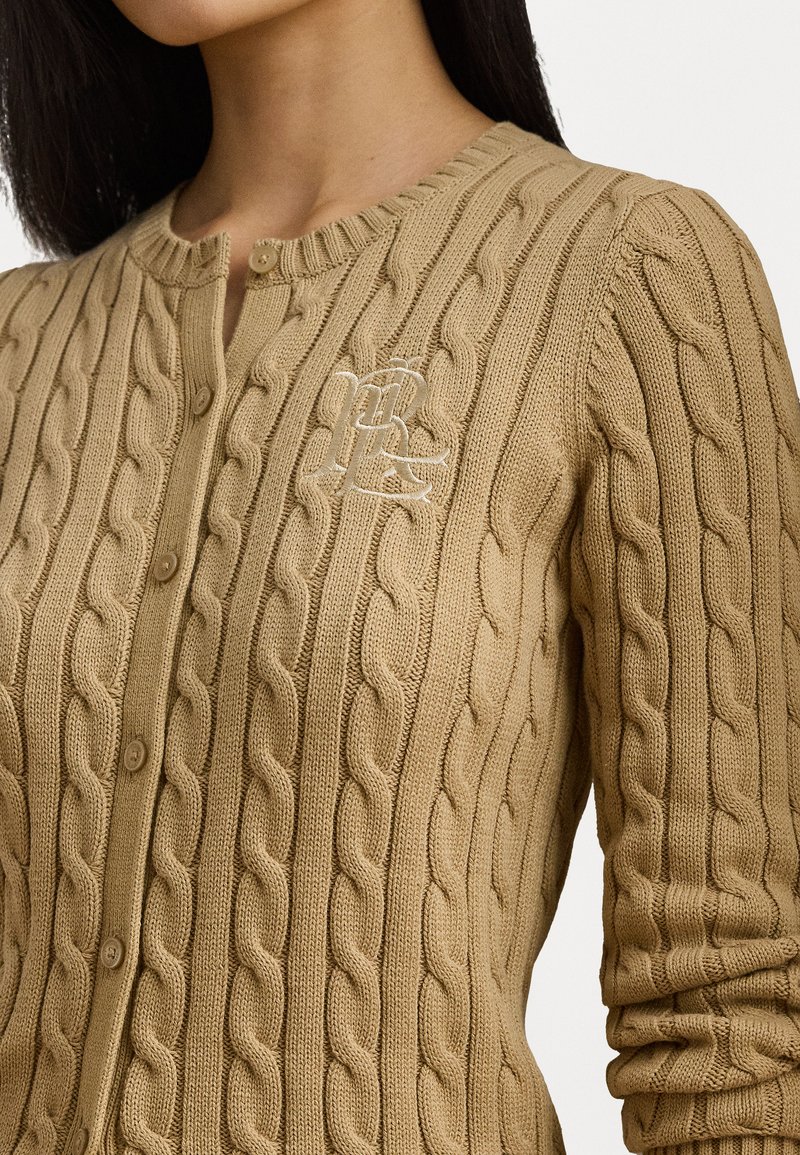 Beige Kabelstrick-Cardigan mit strukturiertem Muster, runder Ausschnitt und Vorderknöpfen. Gesticktes Logo auf der linken Brust.