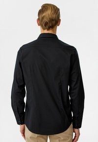 Zwarte langemouwen shirt met een op maat gemaakte pasvorm, knoopmanchetten en een zachte textuur. Bevat een klassieke kraag en een rug yoke-detail.