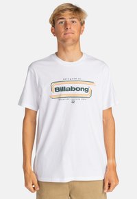 White cotton t-shirt featuring a central multi-colored graphic with "Billabong" text. Short sleeves and a round neckline.