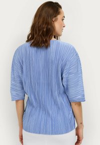 Blaue plissierte Bluse mit lässigem Schnitt, kurzen Ärmeln, vertikalen Streifen und rundem Ausschnitt. Weicher Stoff und leichtes Material.