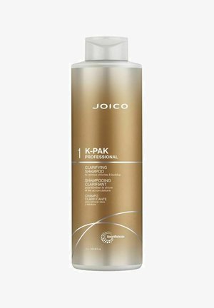 Joico K-Pak Professional 1 L kirkastava shampoossa on korkea, sylinterimäinen kultainen pullo, jossa on valkoisia yksityiskohtia ja läpinäkyvä korkki, ja se on varustettu monikielisillä teksteillä.