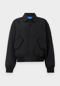 Μαύρο μπουφάν bomber με φερμουάρ, δύο μεγάλες τσέπες με καπάκι μπροστά, ριμπ μανσέτες και τελείωμα, και μια μικρή τσέπη με φερμουάρ στο αριστερό μανίκι.