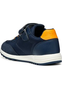 Marineblauwe sneaker met een bovenwerk van suede en textiel, klittenbandsluiting, oranje accent op de hiel en een witte rubberen zool met een gestructureerde grip.