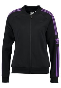 Svart zip-up jacka med lila ränder längs axlar och ärmar. Tillverkad av slätt tyg med ribbade ärmslut och en minimalistisk logotyp på bröstet.