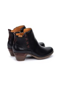 Botas de cuero negras hasta el tobillo con tacones de madera apilados, acentos de costura marrón, cremallera lateral y costura decorativa en forma de cruz cerca del cuello.