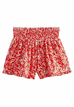 Shorts rouges avec un motif floral blanc. Dotés d'une taille smockée et d'un ourlet froncé, fabriqués en tissu léger.