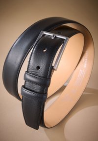 Ceinture en cuir noir à finition lisse, boucle rectangulaire argentée et trous réglables. Caractérisée par des coutures minimales et un intérieur contrastant.