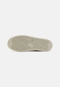 Light gray sneaker sole with textured wave pattern and brand logo. Material appears rubber with a smooth finish for traction and durability.