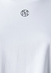 White cotton t-shirt with a small black circular logo featuring "NYC" at the center, displaying a simple and clean design.