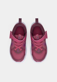 Încălțăminte sportivă de culoare mov și bordeaux, cu partea superioară din plasă, guler căptușit și sfori plata. Dispune de un tablou în formă de buclă și accente de logo contrastante.