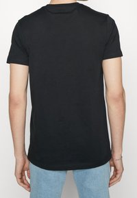 Svart kortärmad t-shirt med rund hals, tillverkad av mjuk bomull, med en rak fåll och en slät textur. Minimalistisk design.