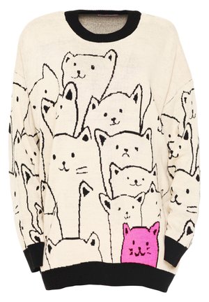 Personne portant un pull beige oversize avec des poignets et un col noirs, orné de plusieurs visages de chats esquissés en noir et d'un chat rose vif, associé à un pantalon large beige et des chaussures noires.