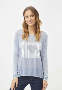 Camiseta de manga larga de color azul claro con un gráfico blanco que presenta líneas verticales y un diseño de corazón en el centro. Tela suave y texturizada.