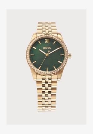 Gouden polshorloge met groene wijzerplaat, kristallen bezette lunette, gouden uurmarkeringen en schakelarmband, toont de tijd 10:09:37.