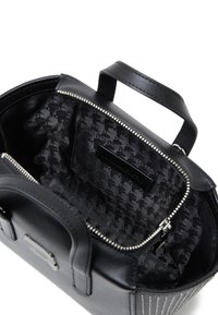 Borsa a tracolla in pelle nera con chiusura a zip. L'interno presenta un motivo a quadri houndstooth neri e un'etichetta piccola su un rivestimento in tessuto liscio.