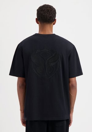 Zwarte katoenen T-shirt met korte mouwen, met een reliëf grafisch logo op de rug. Regular fit met een ronde halslijn, minimale textuur.