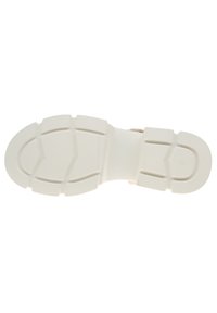 Kengän pohja, jossa on teksturoitu, joustava valkoinen kumimateriaali, Segmented design ja kiinteä pito-kuvio.