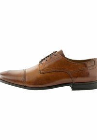 Zapato de vestido de cuero marrón con punta afilada y acabado liso. Presenta un diseño con cordones, costuras sutiles y una suela baja de goma negra.