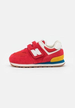 Czerwony dziecięcy tenisówka dla malucha z paskiem na rzep, białym logo "N", panelami z siateczki i zamszu, żółtym akcentem na pięcie oraz gumową podeszwą na białym tle.