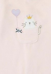 Tela rosa con un gato bordado en un bolsillo, que lleva una corona y sostiene un globo en forma de corazón con un lazo blanco y negro.