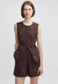 Bruin linnen mouwloze playsuit met gouden kraalborduursel, knopen aan de voorkant en patchzakken op de taille. Op maat gemaakt pasvorm met korte pijpen.