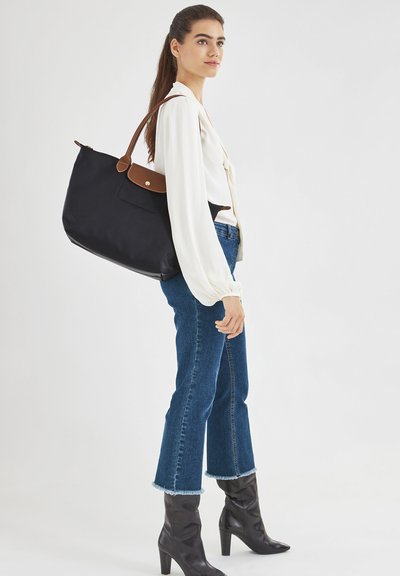 Schwarze Tragetasche aus Nylon mit braunen Lederverzierungen und Akzenten, ausgestattet mit einem Reißverschluss und einem bequemen Schultergurt.