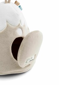 Juguete de peluche suave en color beige con una parte superior blanca, que presenta una cara redonda, una boca hueca y una pequeña etiqueta con el logo "done by deer".