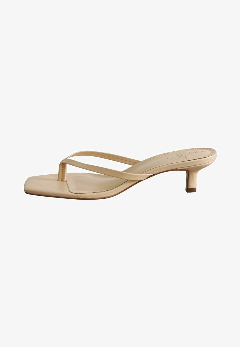 Sandali beige con tacco a blocco e punta quadrata. Realizzati in materiale liscio, presentano cinturini sottili e un tacco basso.