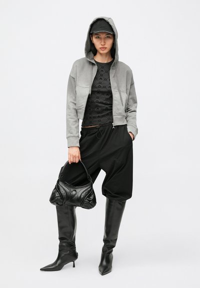 Γκρι cropped φούτερ με κουκούλα, μαύρο τοπ με μοτίβα, χαλαρό μαύρο παντελόνι, μαύρα ψηλοτάκουνα μπότες μέχρι το μηρό και μαύρη τσάντα με υφή.