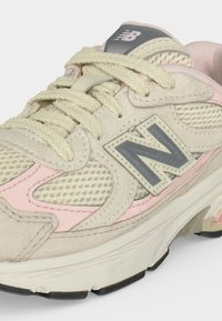 Μπεζ και ροζ αθλητικό παπούτσι New Balance με πλέγμα και πάνελ από σουέτ, χονδρά κρεμ κορδόνια και λευκή ενδιάμεση σόλα με μαύρες λεπτομέρειες στην εξωτερική σόλα.