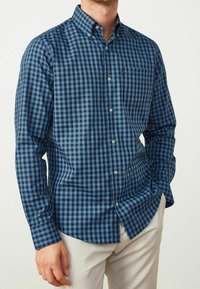 Niebieska i granatowa koszula w kratę z długim rękawem, kołnierzykiem zapinanym na guziki, przednią kieszenią i białymi guzikami, wykonana z miękkiej mieszanki bawełny.