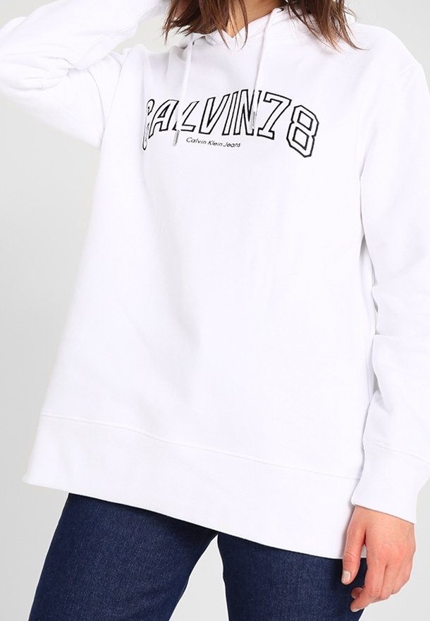 Bílá mikina s kapucí, na které je černý grafický nápis "CALVIN78" a text "Calvin Klein Jeans". Dlouhé rukávy a volný střih.
