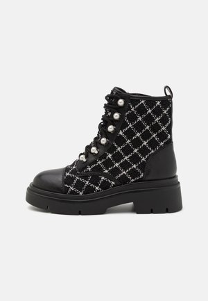 Mustvalge ankle boot, millel on tikandit meenutav tekstuur, pärlitaolised augud, nahkadetailid ning paks tald. Omandab nööreldava disaini ja tõmbeosa.