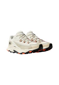 Zapatillas de trail de color beige claro con parte superior de malla texturizada, suela de goma negra, acentos naranjas y cordones reflectantes. Presentan un diseño acolchado para mayor comodidad.