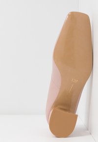 Chaussure plate en cuir rose reposant sur le côté, mettant en évidence la semelle lisse et un petit talon avec un marquage de taille 37 sur fond blanc.