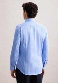 Camicia a maniche lunghe di colore azzurro chiaro con strisce verticali bianche. Tessuto in cotone, orlo arrotondato e polsini con bottoni. Design del colletto classico.