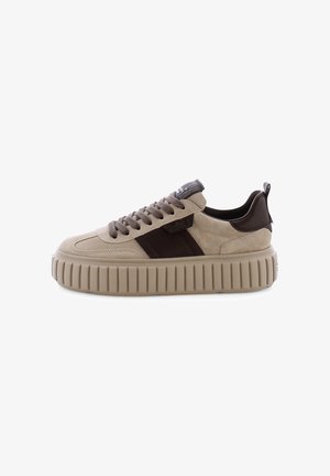 Tan suede sneakers with brown leather accents. Chunky ridged sole, round toe, and flat laces. Features a logo on the tongue.
